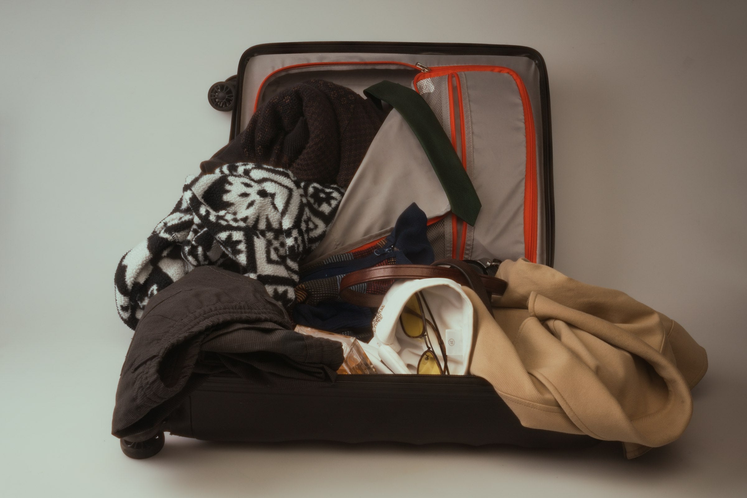 Open suitcase overflowing with messy unfolded clothes